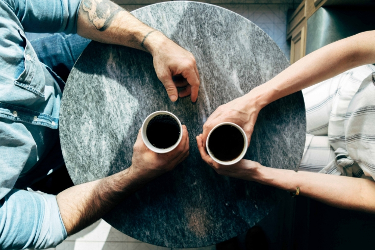 A couple sits at a table with their coffee mugs