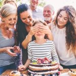 Grandparents, cousins and parents gather around a girl and her birthday cake