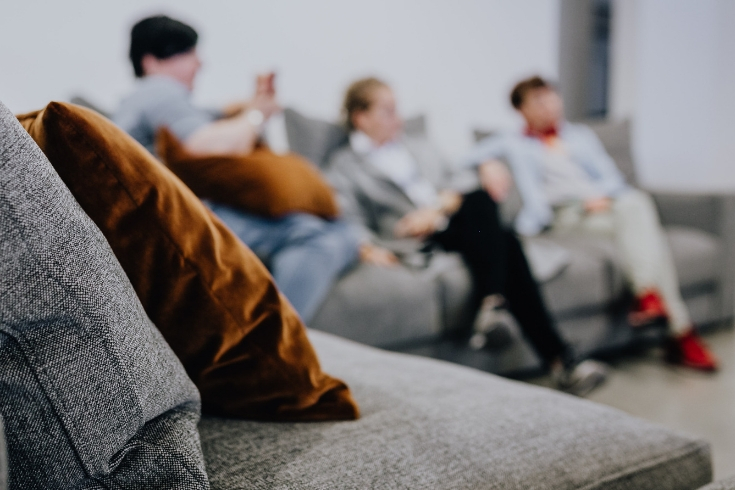 Group of friends sits on gray sectional couch